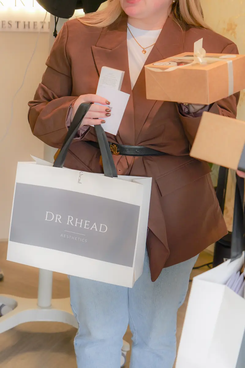 A guest leaving The Signature Event with a Dr Rhead Aesthetics goodie bag and a grazing box.
