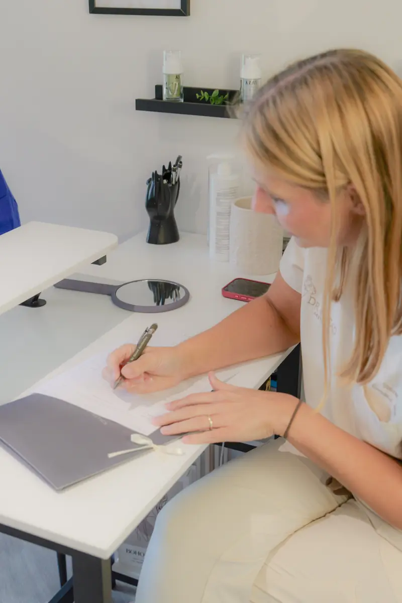 A member of the team writing a personalised skincare plan at a consultation desk in the clinic.
