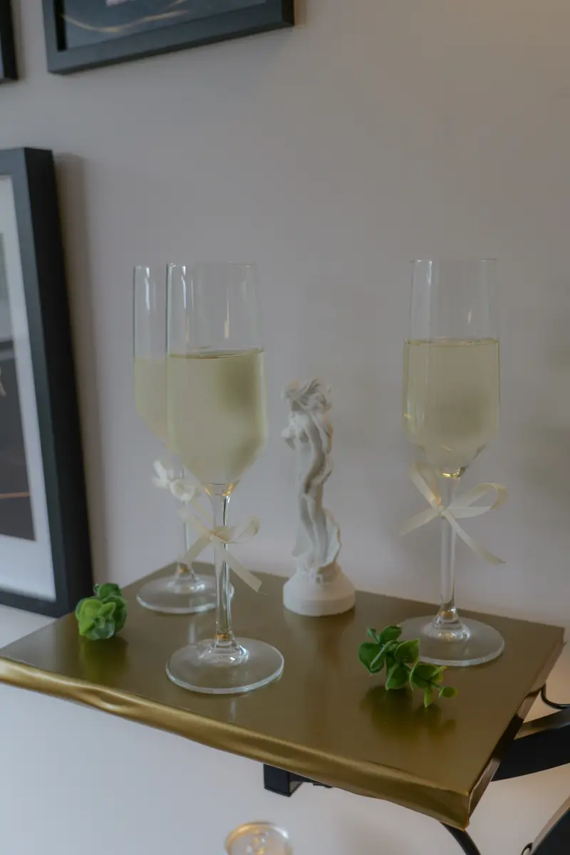 Champagne flutes of prosecco tied with cream ribbon on a gold shelf at Dr Rhead Aesthetics.